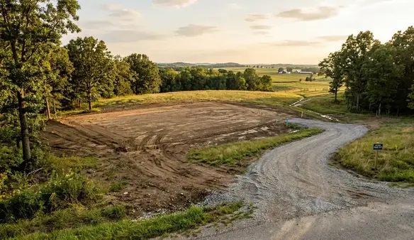 Cleared rural homesite with driveway access and open building area prepared for future construction