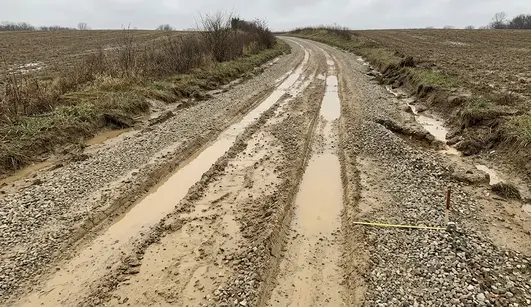 Failed gravel driveway showing rutting, standing water and unstable clay soil conditions in North Missouri