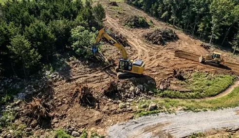 Aerial view of a North Missouri land clearing project showing dense cedar thickets, mature timber, rolling terrain, drainage features, equipment access routes, stumps, and debris piles that influence land clearing costs