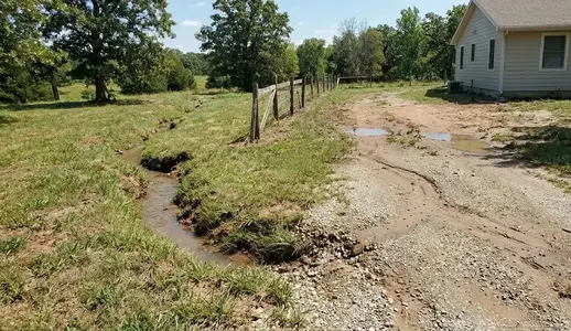 Long-term drainage damage causing erosion, driveway washouts, standing water, and soil instability on a North Missouri property