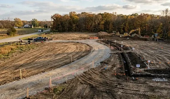 Cleared land transitioning into grading, driveway, and construction preparation phases