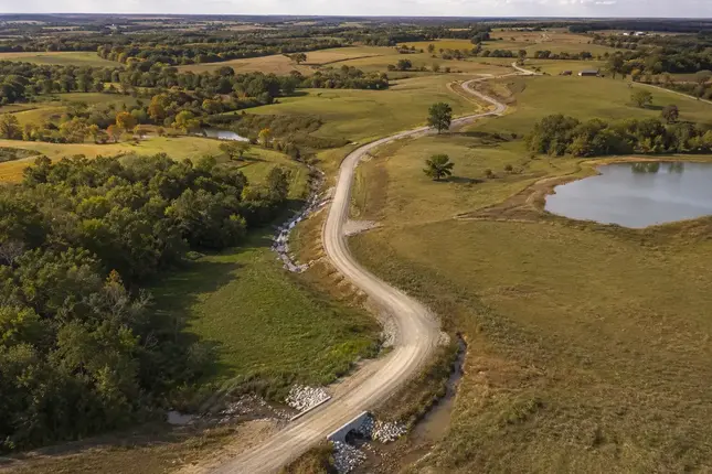 Road construction across rolling farmland, clay hills, timber ground, and drainage terrain in North Missouri